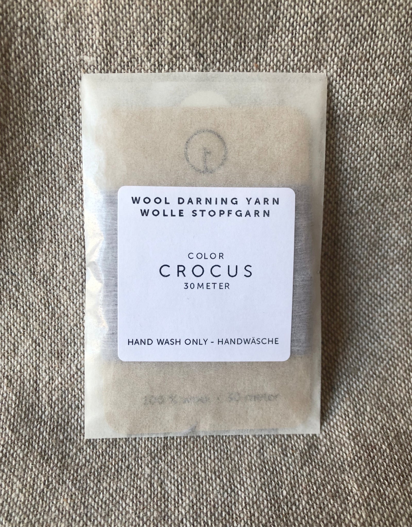 A 30-meter card of 100% wool darning yarn in light purple colour, neatly wound and ready for mending knit garments. The yarn is packaged in a small, eco-friendly parchment paper bag.