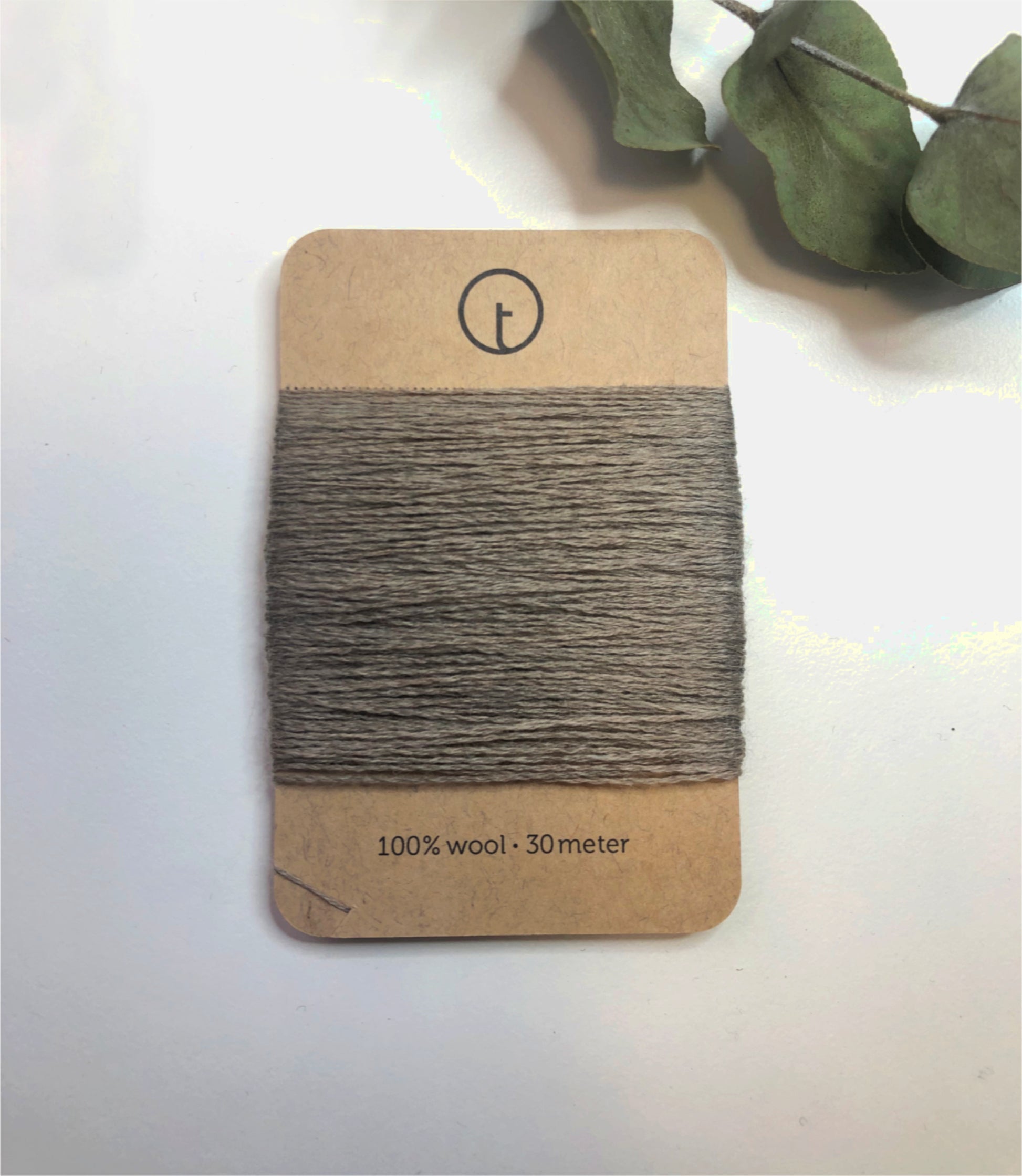 A 30-meter card of 100% wool fine darning yarn in logwood (dark beige/grey) colour, neatly wrapped around a labeled rectangular paper card, ideal for repairing knitwear.
