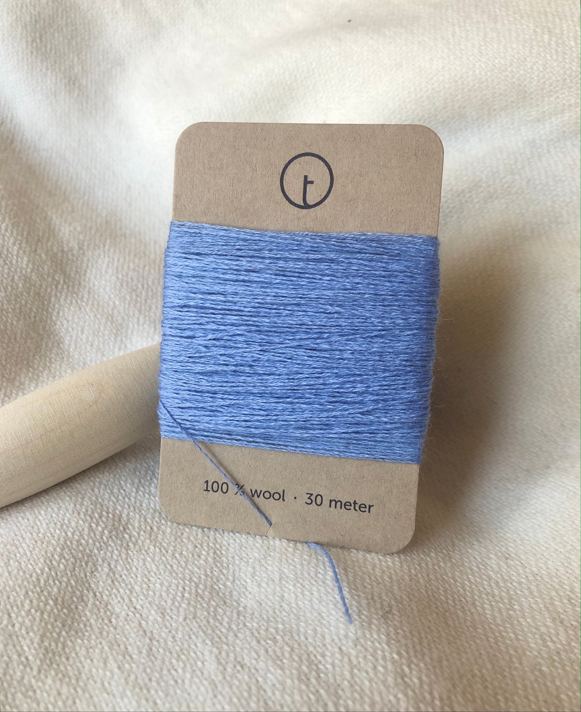 Powder blue 100% wool darning yarn in Powder blue color neatly wrapped around a rectangular paper card, ideal for repairing knit clothing.