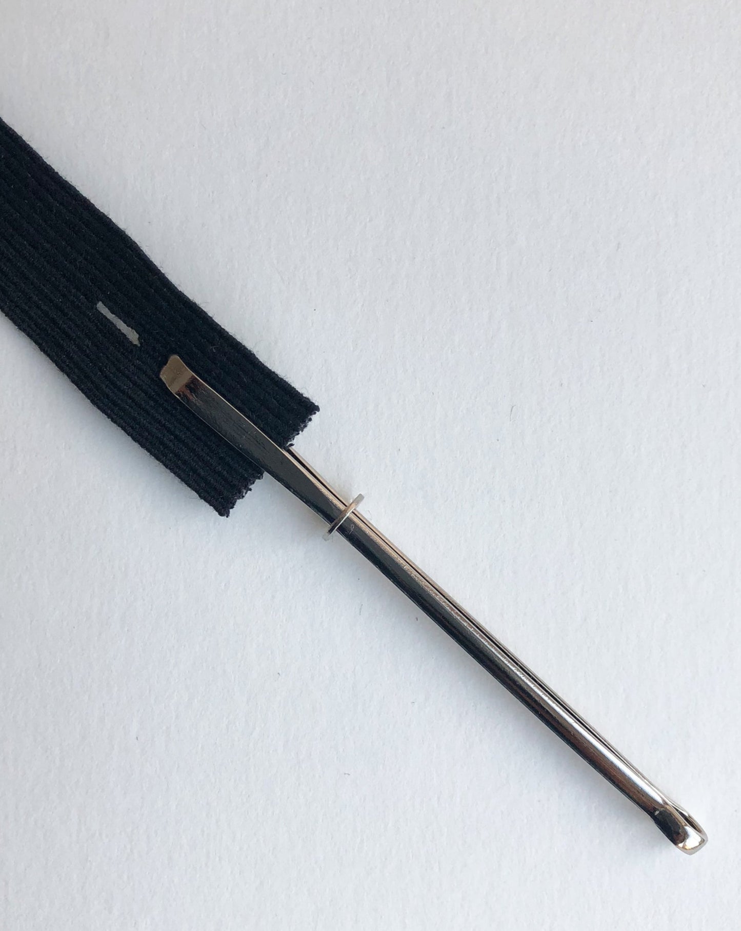 A bodkin will be opened and closed by sliding a little metal ring. Open to insert a string or ruber band, close to secure them in between tweezers, then the bodkin will be threaded the casing.