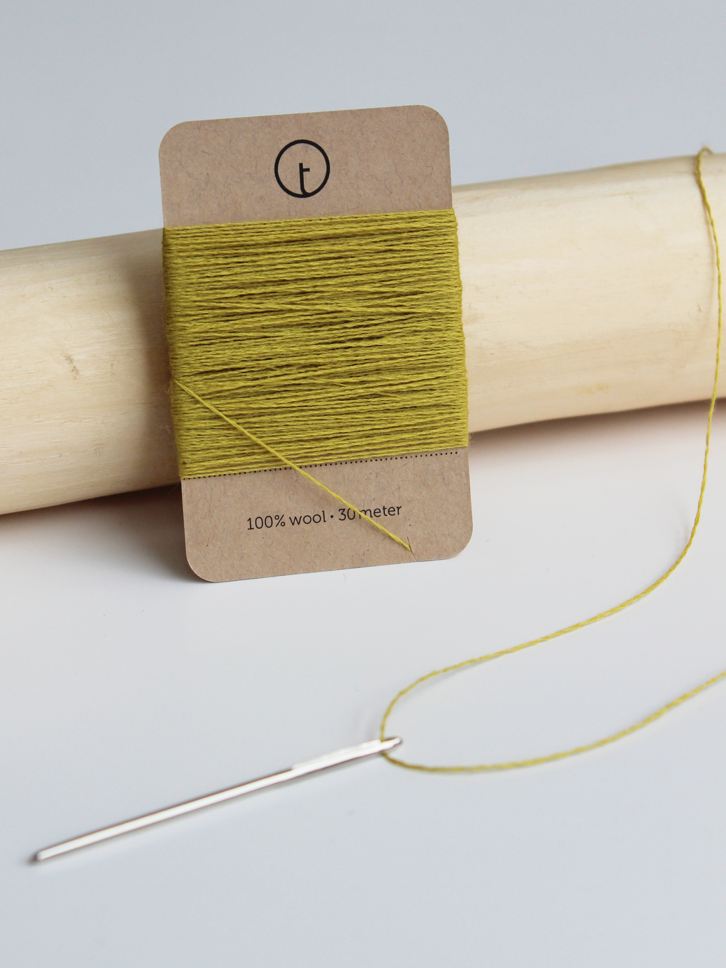 A 30-meter card of 100% wool fine darning yarn in straw (golden yellow) colour, neatly wrapped around a labeled rectangular paper card, ideal for repairing knitwear.
