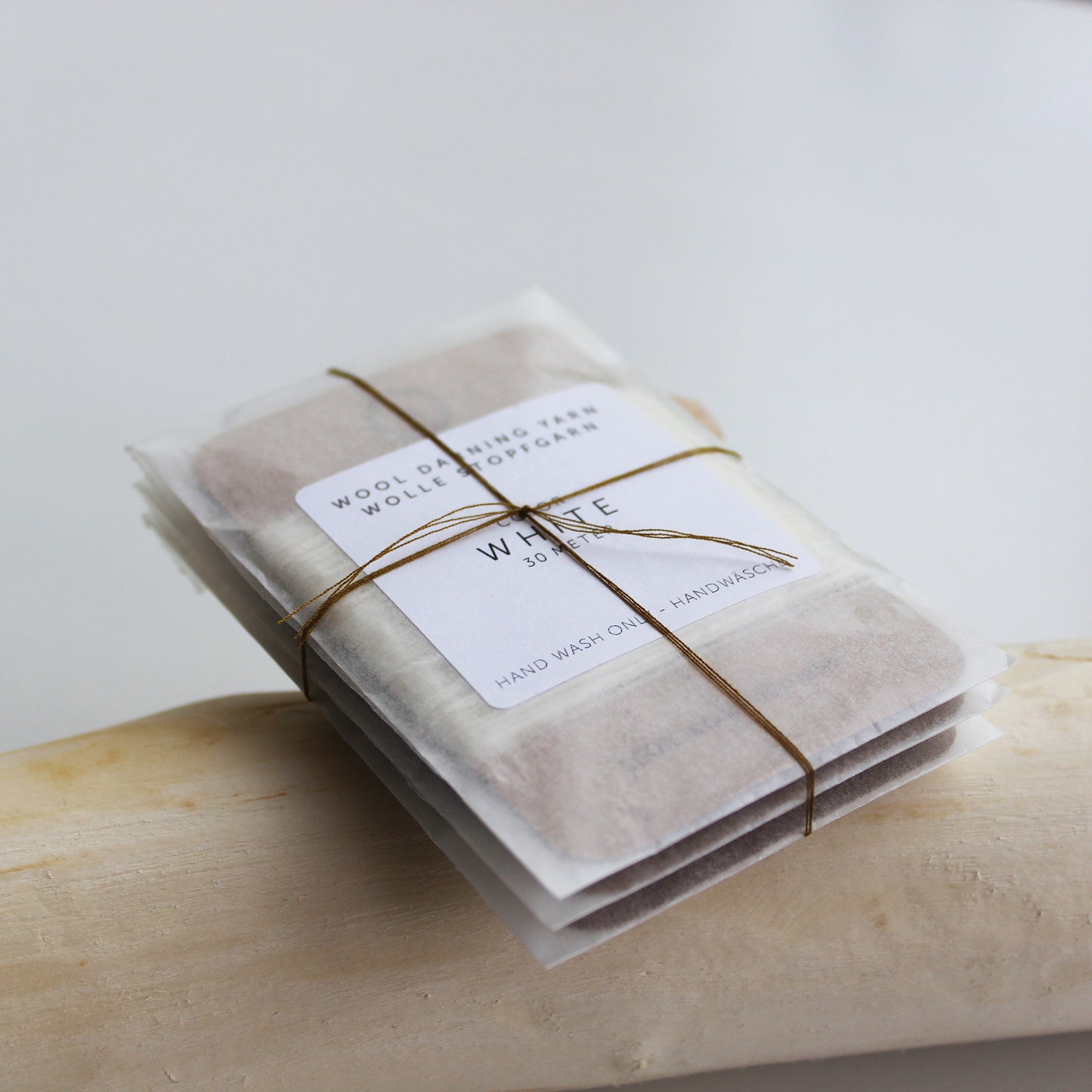 A 30-meter card of 100% wool darning yarns in assorted colours, neatly wound and ready for mending knit garments. The yarn cards are packaged in a small, eco-friendly parchment paper bag.