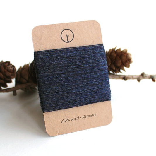 A 30-meter card of 100% wool fine darning yarn in Navy colour, neatly wrapped around a labeled rectangular paper card, ideal for repairing knitwear.