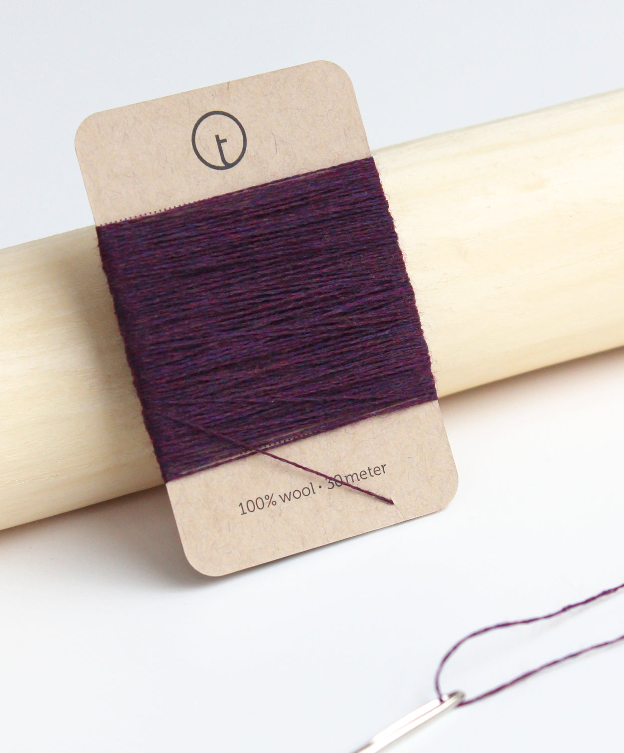 A 30-meter card of 100% wool fine darning yarn in prune purple colour, neatly wrapped around a labeled rectangular paper card, ideal for repairing knitwear.
