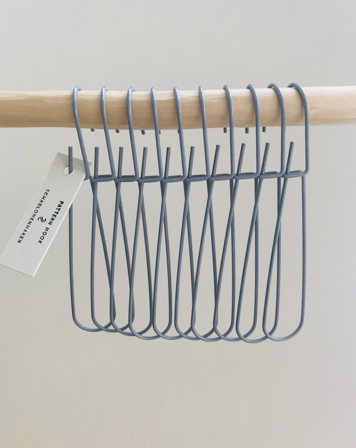 Set of 10 heavy-duty steel wire hooks in two sizes: large (18 cm long, 12.5 cm loop, 3.5 cm wide) and small (11.5 cm long, 8.5 cm loop, 2 cm wide). Made in Germany, designed for organizing patterns, tools, and scissors. Plastic-free with a spring-clip loop. Matte, powdery finish that becomes smooth over time.