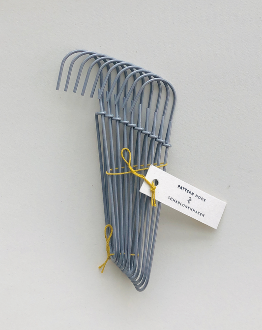 Set of 10 heavy-duty steel wire hooks in two sizes: large (18 cm long, 12.5 cm loop, 3.5 cm wide) and small (11.5 cm long, 8.5 cm loop, 2 cm wide). Made in Germany, designed for organizing patterns, tools, and scissors. Plastic-free with a spring-clip loop. Matte, powdery finish that becomes smooth over time.