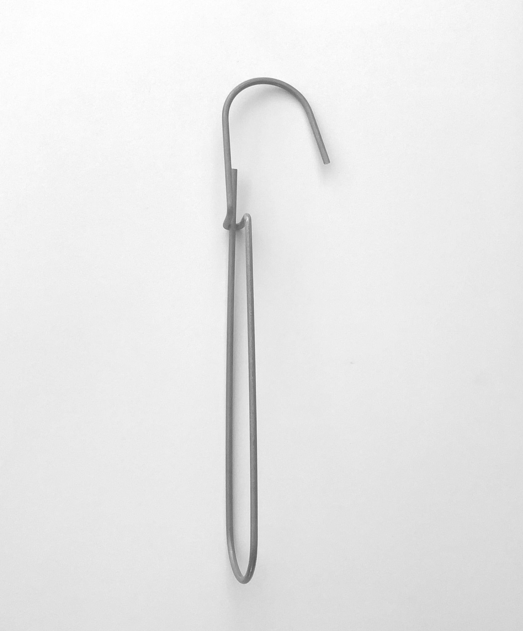 Heavy-duty steel wire hook available in two sizes: large (18 cm long, 12.5 cm loop, 3.5 cm wide) and small (11.5 cm long, 8.5 cm loop, 2 cm wide). Made in Germany, designed for organizing patterns, tools, and scissors. Plastic-free with a spring-clip loop. Matte, powdery finish that becomes smooth over time.
