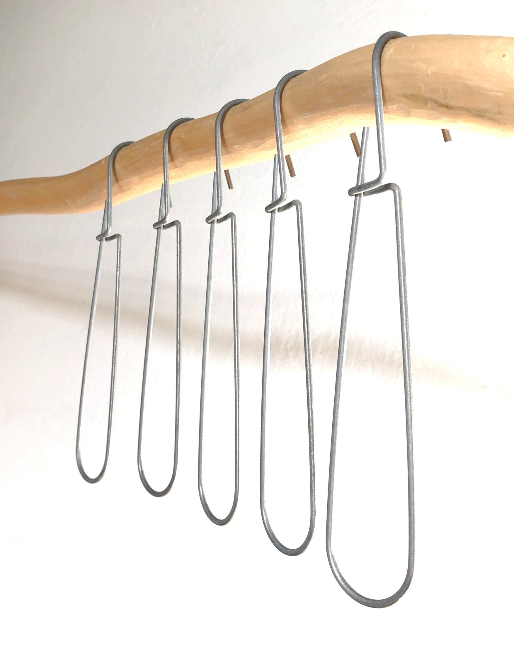 "Set of 5 or 10 heavy-duty steel wire hooks in two sizes: large (18 cm long, 12.5 cm loop, 3.5 cm wide) and small (11.5 cm long, 8.5 cm loop, 2 cm wide). Made in Germany, designed for organizing patterns, tools, and scissors. Plastic-free with a spring-clip loop. Matte, powdery finish that becomes smooth over time."
