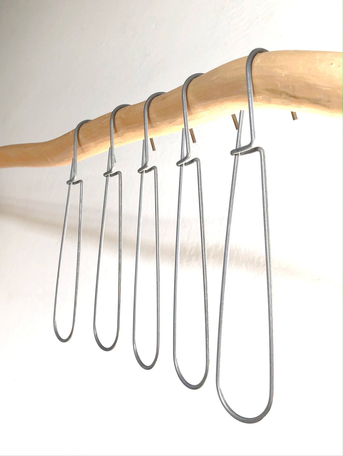Set of 5 heavy-duty steel wire hooks in two sizes: large (18 cm long, 12.5 cm loop, 3.5 cm wide) and small (11.5 cm long, 8.5 cm loop, 2 cm wide). Made in Germany, designed for organizing patterns, tools, and scissors. Plastic-free with a spring-clip loop. Matte, powdery finish that becomes smooth over time.