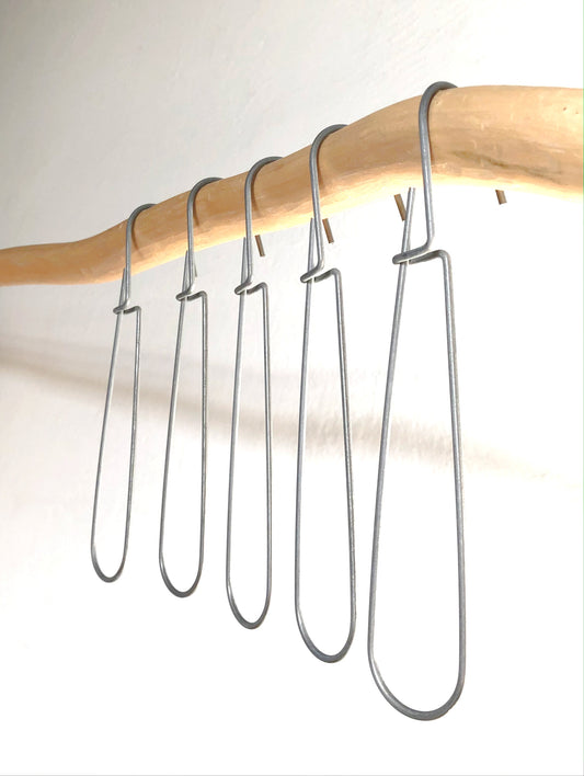 Set of 5 heavy-duty steel wire hooks in two sizes: large (18 cm long, 12.5 cm loop, 3.5 cm wide) and small (11.5 cm long, 8.5 cm loop, 2 cm wide). Made in Germany, designed for organizing patterns, tools, and scissors. Plastic-free with a spring-clip loop. Matte, powdery finish that becomes smooth over time.