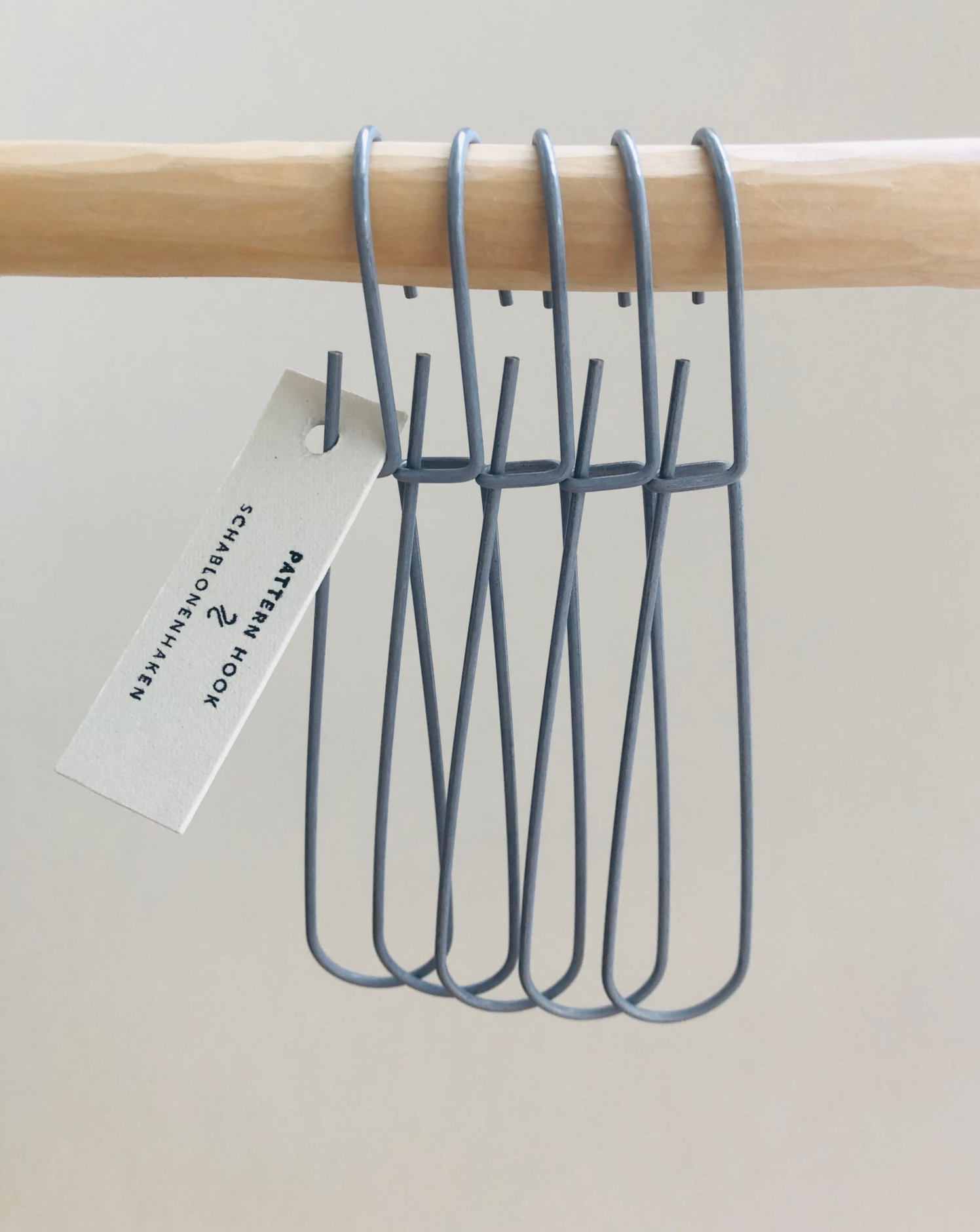 Set of 5 heavy-duty steel wire hooks in two sizes: large (18 cm long, 12.5 cm loop, 3.5 cm wide) and small (11.5 cm long, 8.5 cm loop, 2 cm wide). Made in Germany, designed for organizing patterns, tools, and scissors. Plastic-free with a spring-clip loop. Matte, powdery finish that becomes smooth over time.
