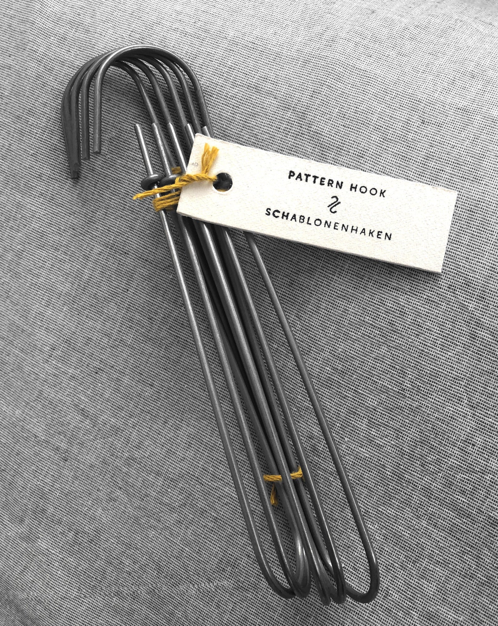 Set of 5 heavy-duty steel wire hooks in two sizes: large (18 cm long, 12.5 cm loop, 3.5 cm wide) and small (11.5 cm long, 8.5 cm loop, 2 cm wide). Made in Germany, designed for organizing patterns, tools, and scissors. Plastic-free with a spring-clip loop. Matte, powdery finish that becomes smooth over time.