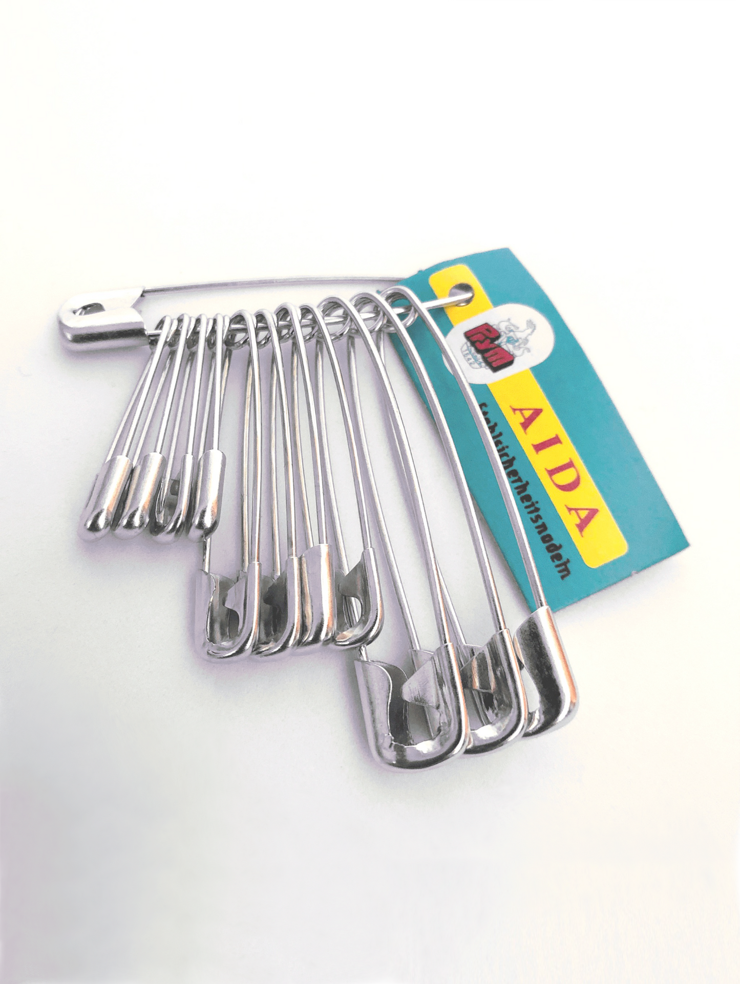 A set of 12 silver safety pins in varying sizes, displayed on a white background, with a paper label indicating the brand 'Prym'.