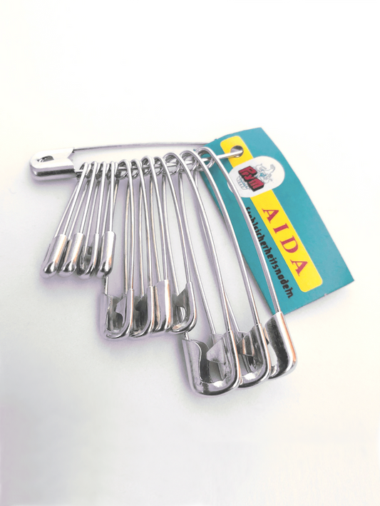 A set of 12 silver safety pins in varying sizes, displayed on a white background, with a paper label indicating the brand 'Prym'.