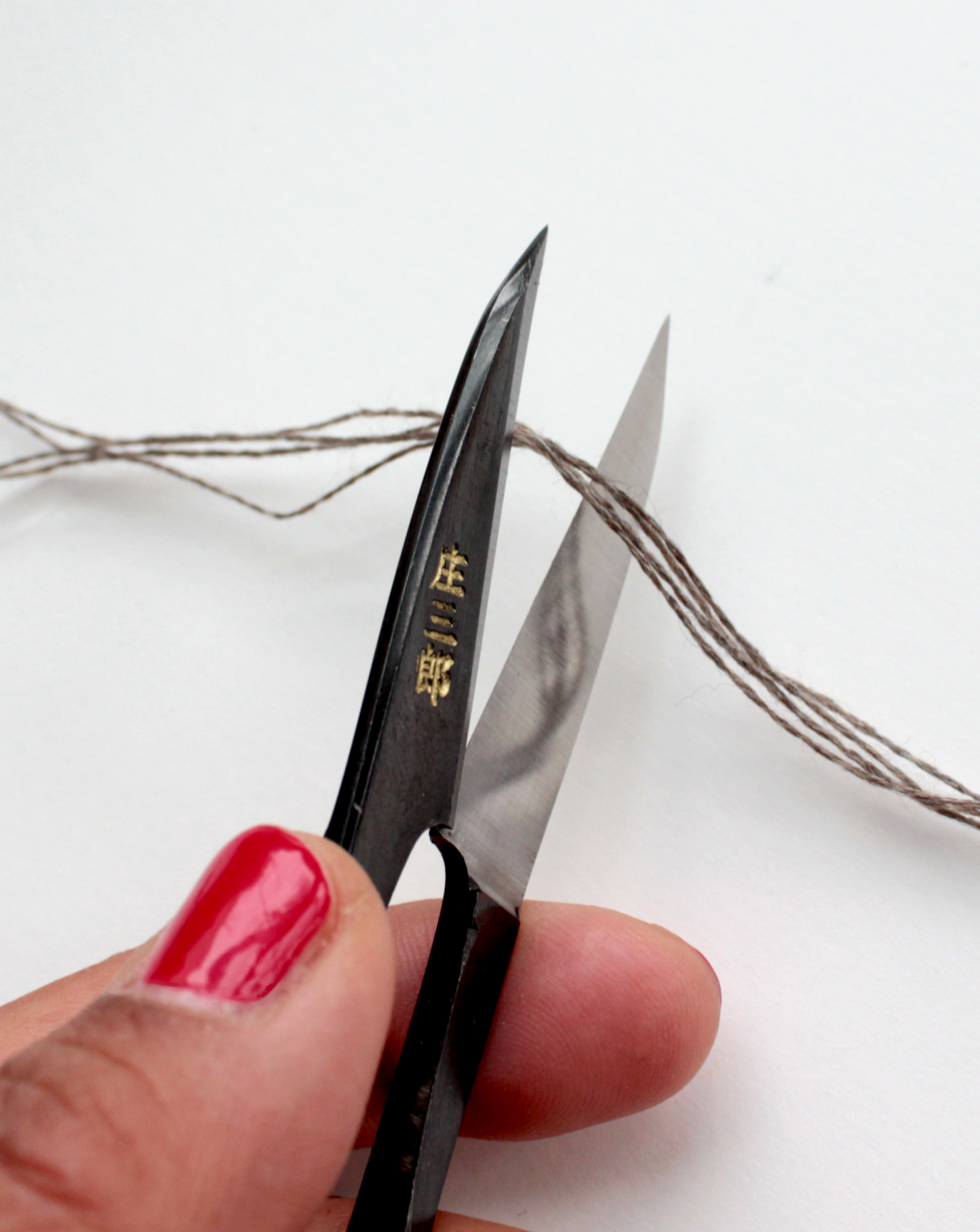 Shozaburo U-shaped thread snips with long 4.5 cm carbon steel blades, designed for precision thread cutting. Compact 10.5 cm size, 30 g weight. Traditional Japanese design in paper wrap packaging, includes English care guide.
