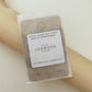 A 30-meter card of 100% wool darning yarn in logwood (dark beige/grey) colour, neatly wound and ready for mending knit garments. The yarn is packaged in a small, eco-friendly parchment paper bag.